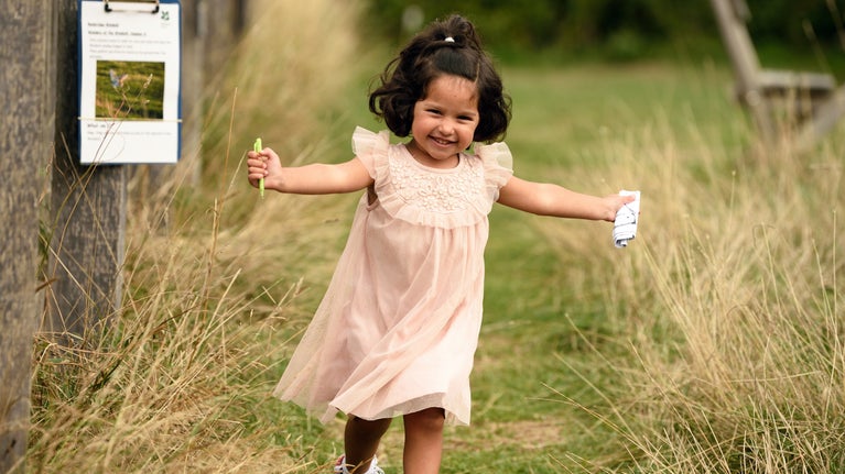 Girl running through the long grass at Bembridge Windmill, Isle of Wight in summer
